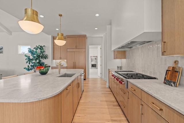 kitchen featuring stainless steel cooktop, light wood-style flooring, decorative backsplash, a sink, and wall chimney exhaust hood