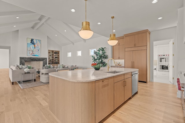 kitchen with light countertops, light wood-style flooring, light brown cabinetry, appliances with stainless steel finishes, and a sink