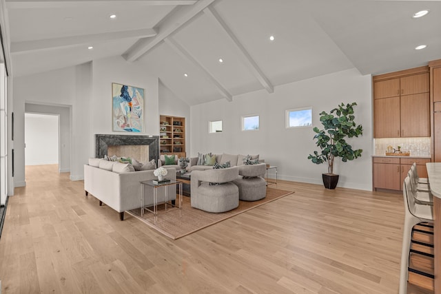 living room with high vaulted ceiling, light wood finished floors, a premium fireplace, and beam ceiling