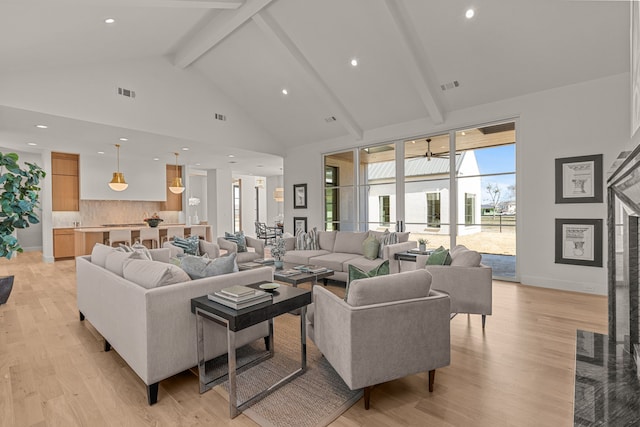 living area with high vaulted ceiling, light wood-style floors, visible vents, and beamed ceiling