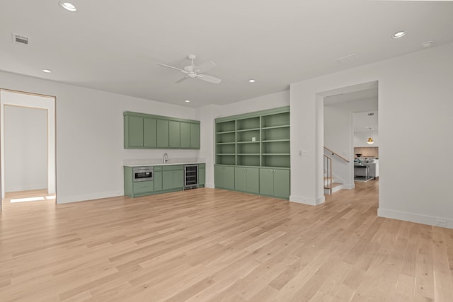 unfurnished living room with light wood finished floors, recessed lighting, a ceiling fan, beverage cooler, and baseboards