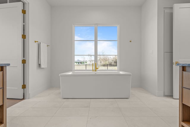 bathroom with a freestanding bath, tile patterned floors, vanity, and baseboards