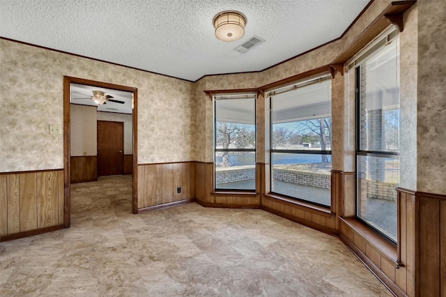 268 Roland Rd, Whitesboro, TX 76273 - spare room with wooden walls, visible vents, a wainscoted wall, a water view, and a textured ceiling