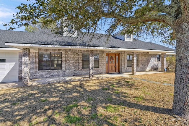 view of front of property with brick siding, an attached garage, and roof with shingles