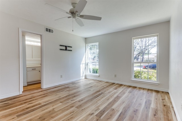 spare room featuring baseboards, ceiling fan, visible vents, and light wood-style floors