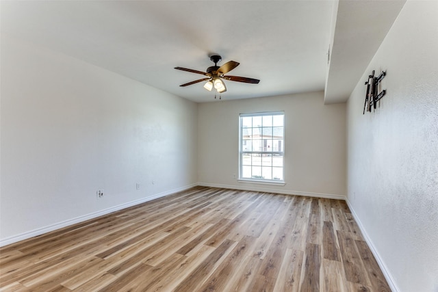 spare room with ceiling fan, light wood finished floors, and baseboards