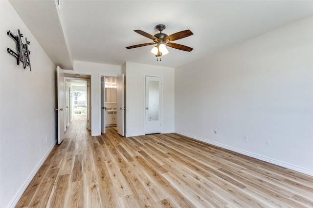 unfurnished bedroom featuring light wood-type flooring, connected bathroom, baseboards, and ceiling fan