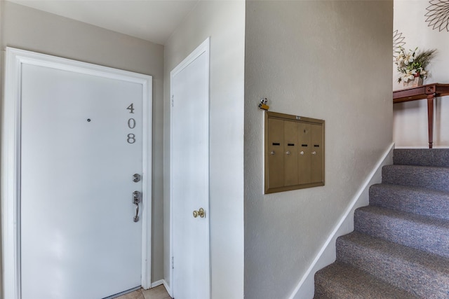 interior space featuring baseboards, mail area, and stairs