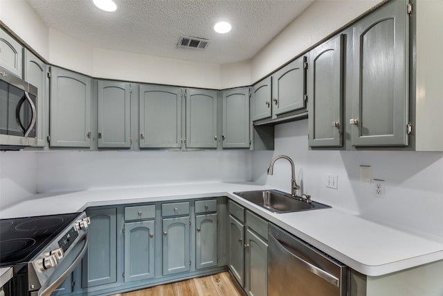 kitchen with visible vents, appliances with stainless steel finishes, light countertops, a textured ceiling, and a sink