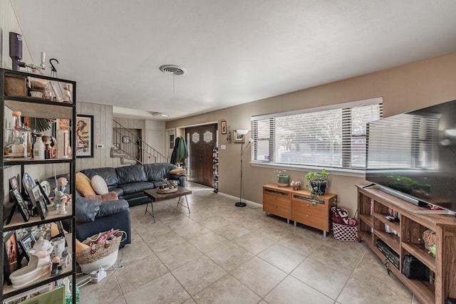 tiled living area with stairs, visible vents, and baseboards