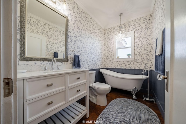 full bathroom with wood finished floors, a freestanding bath, vanity, and wallpapered walls