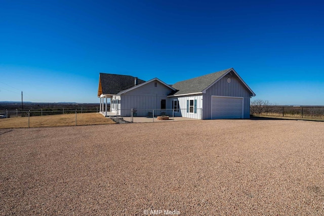 view of front of home featuring board and batten siding, fence, driveway, and a garage