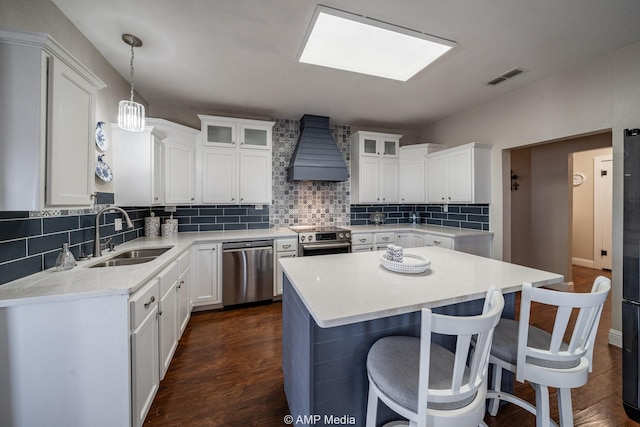 kitchen with tasteful backsplash, a breakfast bar area, stainless steel appliances, premium range hood, and a sink