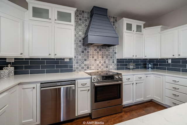 kitchen with custom exhaust hood, stainless steel appliances, light countertops, backsplash, and white cabinetry