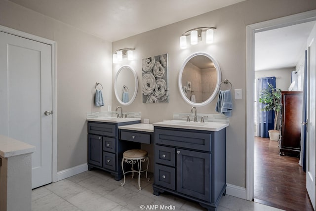 full bath with two vanities, a sink, and baseboards