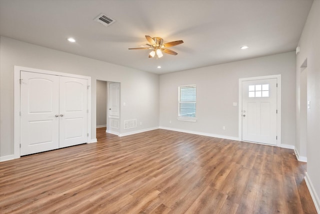 interior space featuring a healthy amount of sunlight, baseboards, visible vents, and wood finished floors