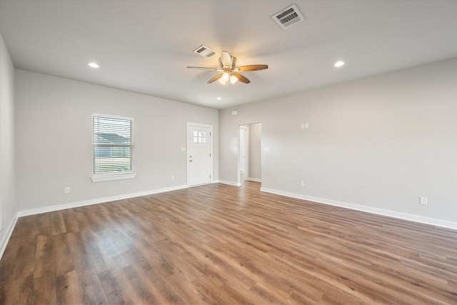 spare room featuring baseboards, ceiling fan, visible vents, and wood finished floors