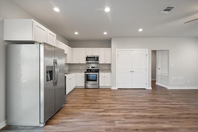 kitchen featuring white cabinets, visible vents, stainless steel appliances, and wood finished floors