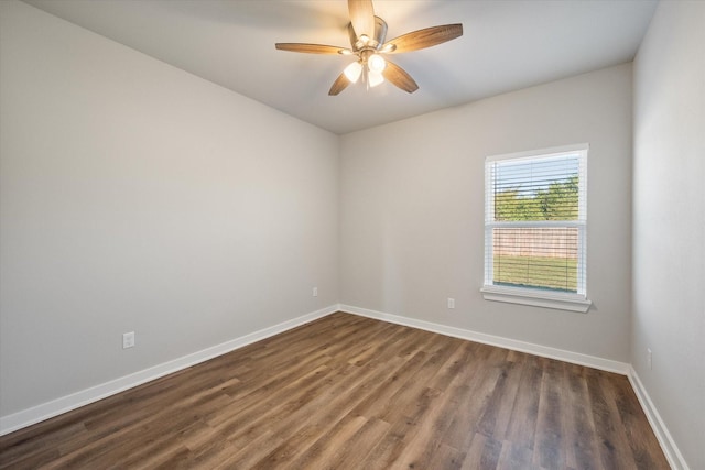 empty room featuring dark wood-style floors, a ceiling fan, and baseboards