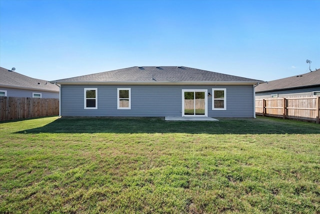 rear view of house with a fenced backyard, a shingled roof, and a lawn