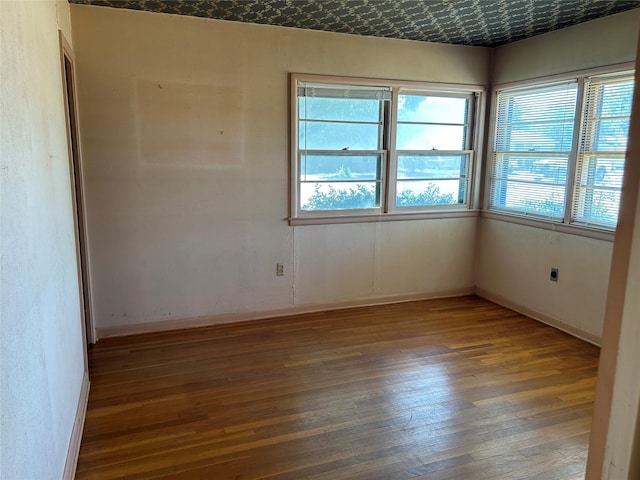 unfurnished room with baseboards and wood finished floors