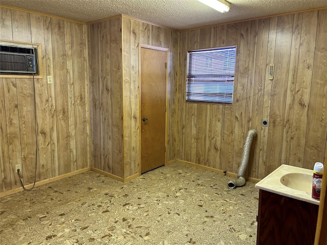 bathroom with baseboards, a wall mounted air conditioner, a textured ceiling, vanity, and wood walls