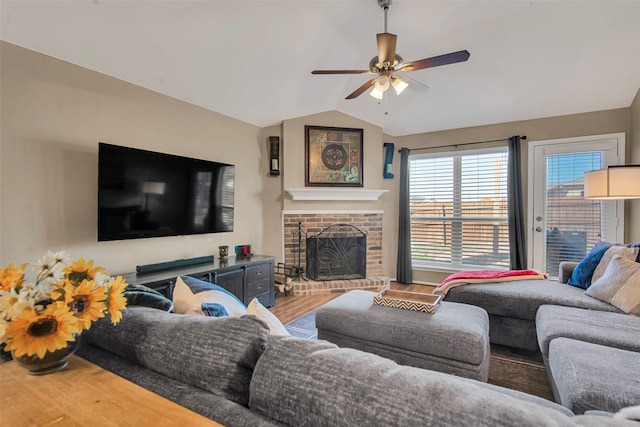 living area featuring vaulted ceiling, a fireplace, wood finished floors, and a ceiling fan