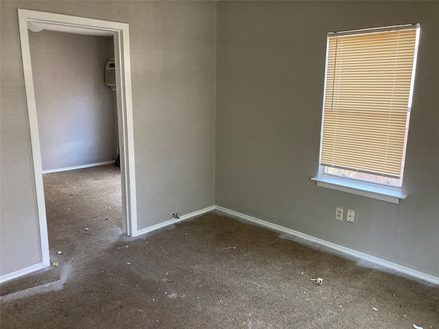 empty room with an AC wall unit and baseboards