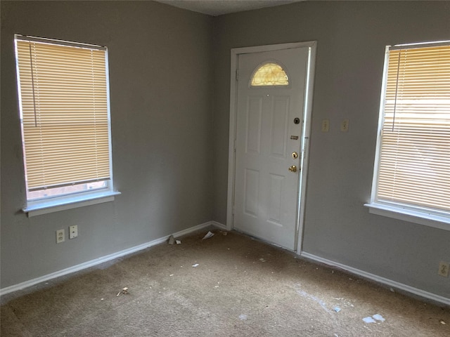 foyer featuring baseboards and carpet flooring