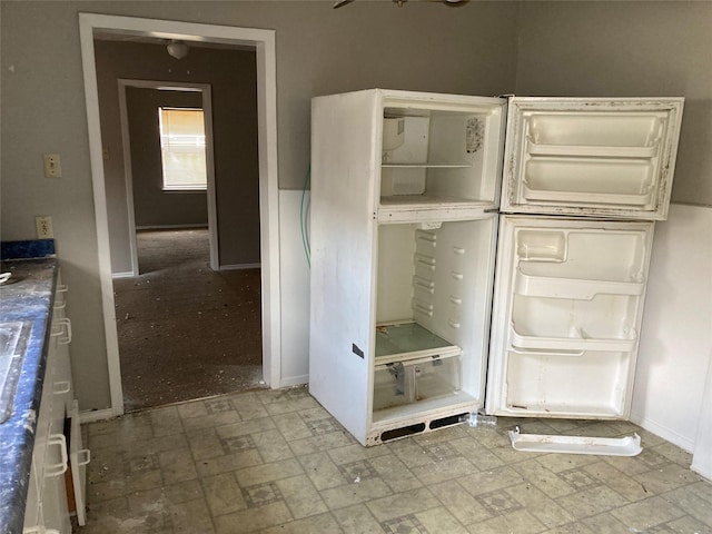 interior space featuring freestanding refrigerator and baseboards