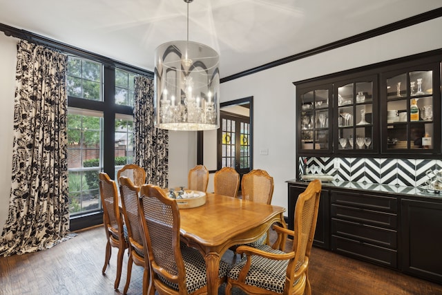 dining room featuring dark wood-style floors, crown molding, and a dry bar