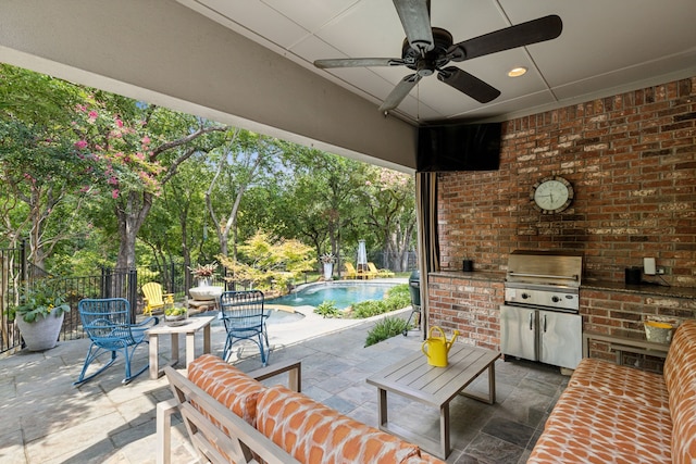 view of patio with fence, a ceiling fan, exterior kitchen, grilling area, and a fenced in pool