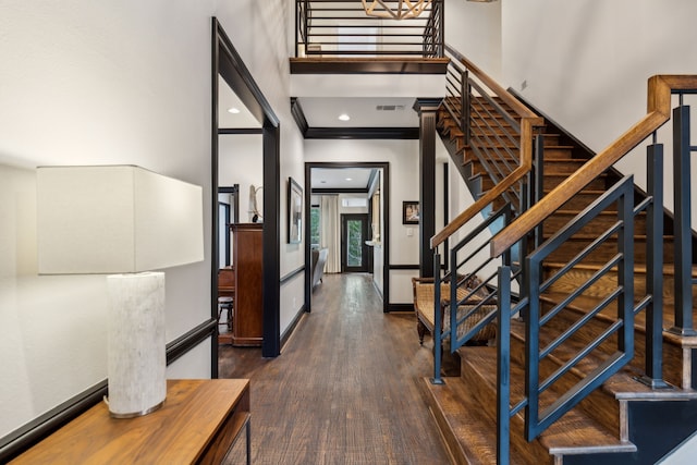 foyer featuring visible vents, a high ceiling, ornamental molding, wood finished floors, and baseboards