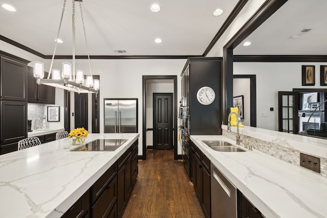 kitchen with light stone counters, pendant lighting, black electric stovetop, a sink, and built in refrigerator