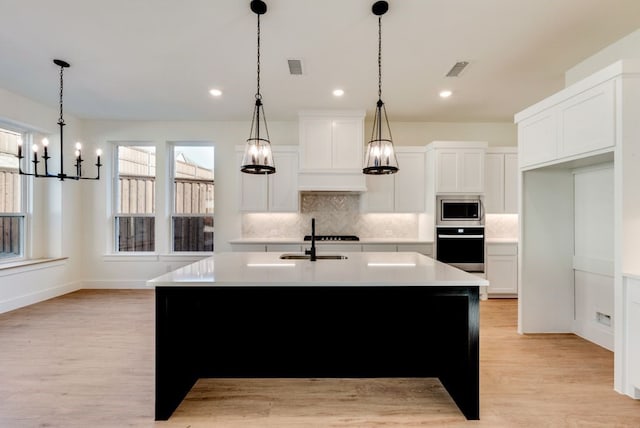 kitchen with stainless steel microwave, light countertops, backsplash, and black oven