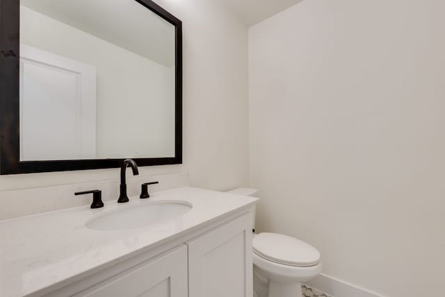 bathroom with toilet, baseboards, and vanity