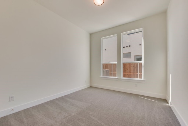 spare room featuring baseboards and light colored carpet