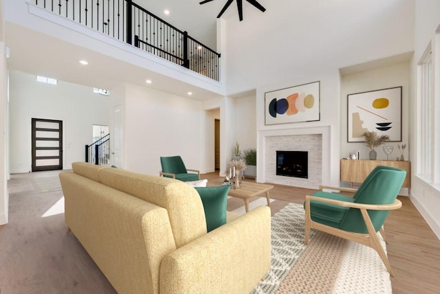 living area with a glass covered fireplace, wood finished floors, a towering ceiling, and baseboards