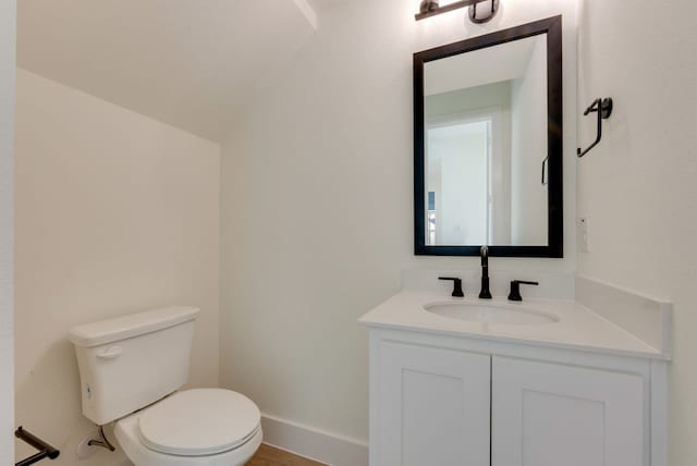 bathroom with toilet, vaulted ceiling, vanity, and baseboards