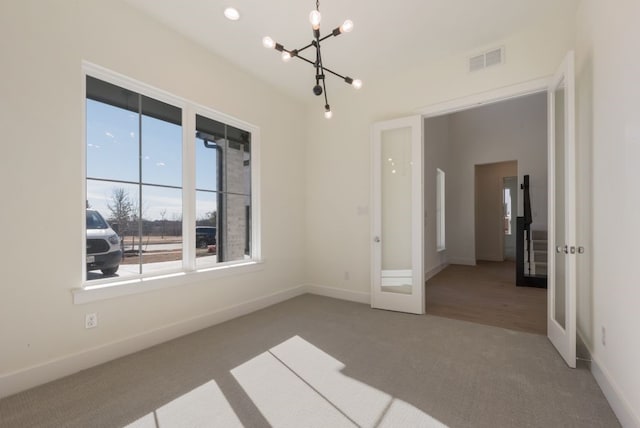 carpeted empty room with a chandelier, french doors, visible vents, and baseboards