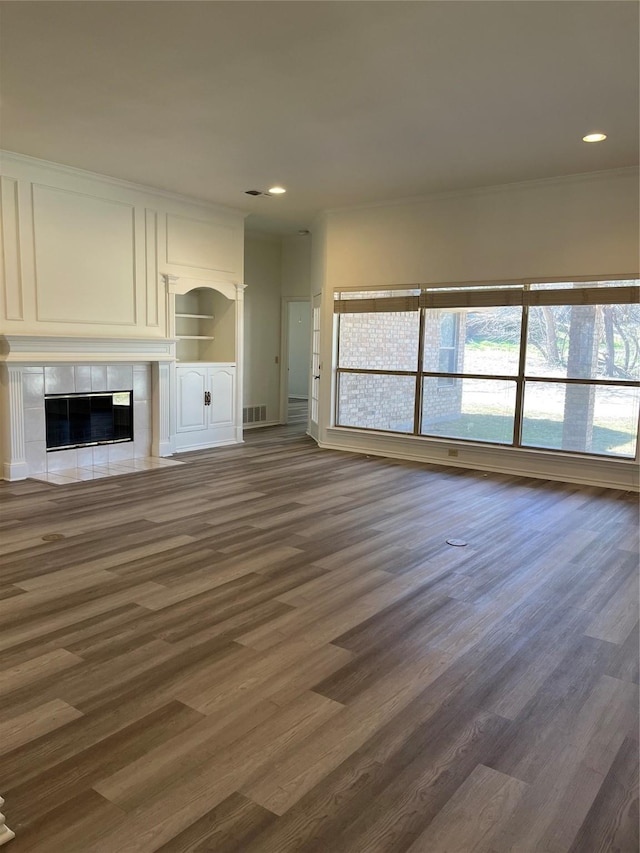 unfurnished living room featuring dark wood-type flooring, a tile fireplace, visible vents, and recessed lighting