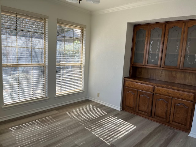 dining area with baseboards, crown molding, and light wood finished floors