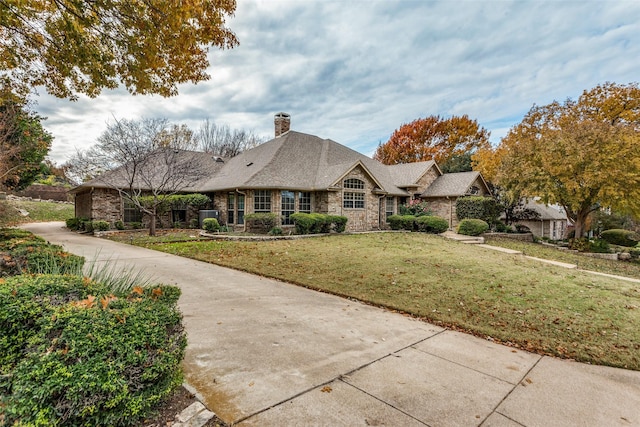 view of front facade with stone siding, driveway, a chimney, and a front lawn