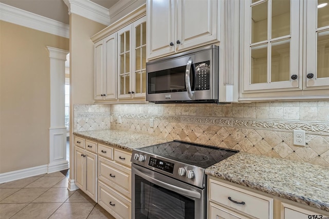 kitchen with light tile patterned floors, cream cabinets, appliances with stainless steel finishes, backsplash, and crown molding