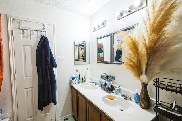 full bathroom with a textured ceiling, double vanity, and a sink