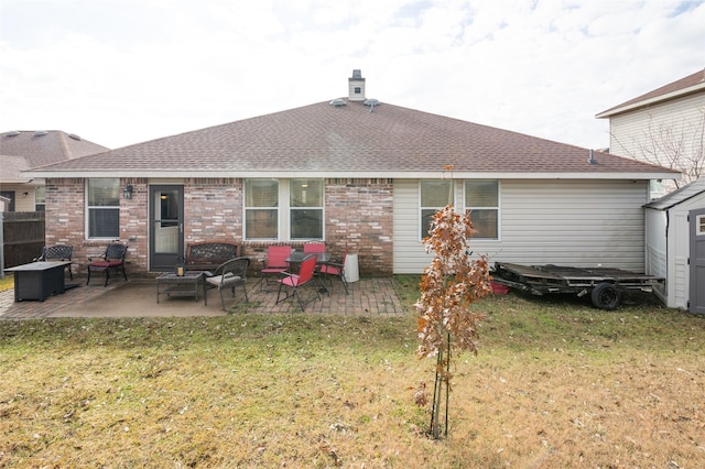 rear view of property with a yard, brick siding, roof with shingles, and a patio area