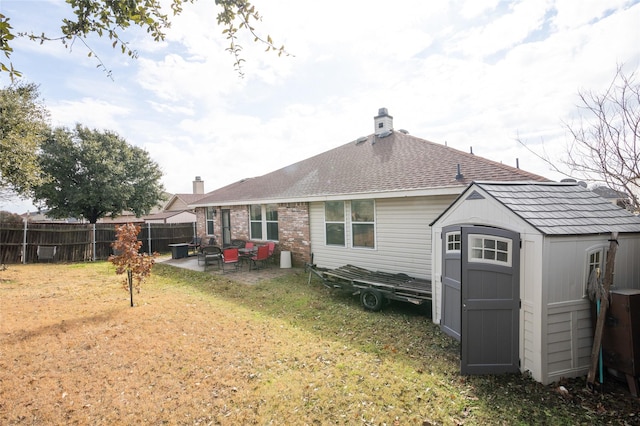 back of property featuring a yard, a patio, a storage unit, fence, and an outdoor structure