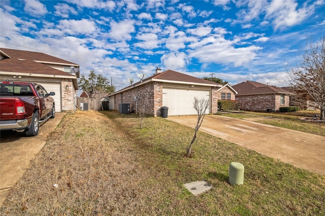 view of home's exterior featuring brick siding, a lawn, a garage, cooling unit, and driveway