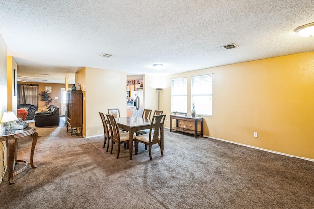 dining space with a textured ceiling, carpet flooring, visible vents, and baseboards