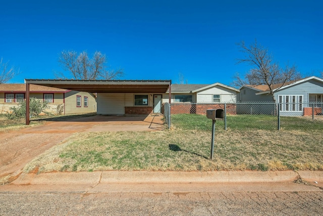 single story home with brick siding, concrete driveway, an attached carport, fence, and a front yard